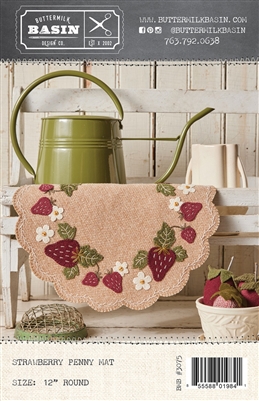 This picture shows a strawberry penny mat with fresh berries and blossoms set in a charming kitchen, with a watering can to remind us how fresh the wool mat feels.