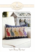 This is a small wool applique pillow featuring a design of five bunnies in Easter colors.