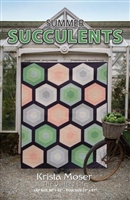 A large Oversized hexagon quilt is shown on the cover of this quilt pattern and features subtle , garden hues of greens, neutrals and peachy tones.