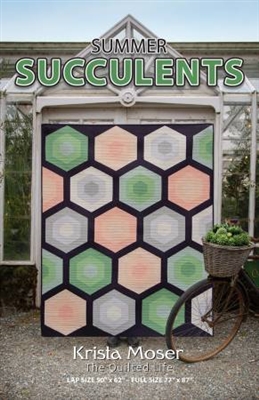 A large Oversized hexagon quilt is shown on the cover of this quilt pattern and features subtle , garden hues of greens, neutrals and peachy tones.